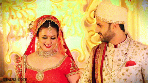 A Bride And Groom Are Posing For A Picture In Their Wedding Outfits GIF