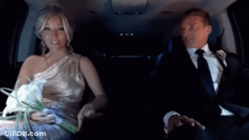 A Bride And Groom Are Sitting In A Car And The Bride Is Holding A Bouquet Of Flowers GIF