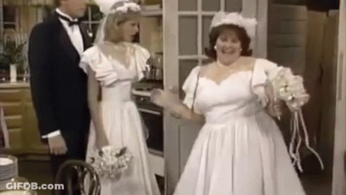 A Bride And Groom Are Standing In A Kitchen . GIF