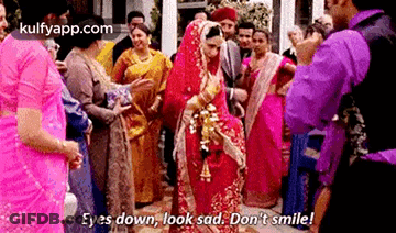 A Bride And Groom Are Standing In Front Of A Crowd Of People . GIF