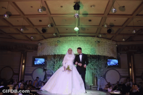 A Bride And Groom Are Walking Down The Aisle At A Wedding Reception GIF