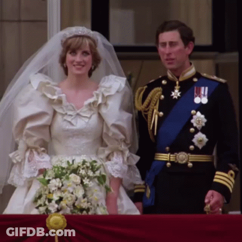 A Bride And Groom Standing Next To Each Other On Their Balcony GIF