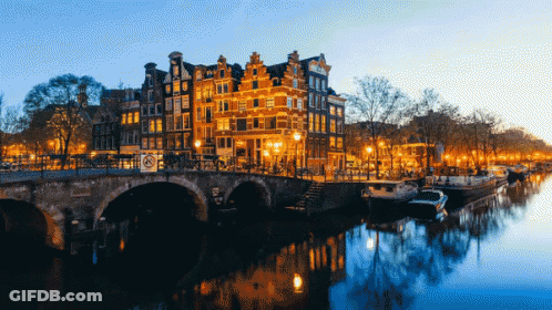 A Bridge Over A River With Buildings In The Background GIF