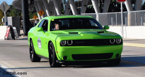 A Bright Green Dodge Challenger Is Driving Down A Road GIF