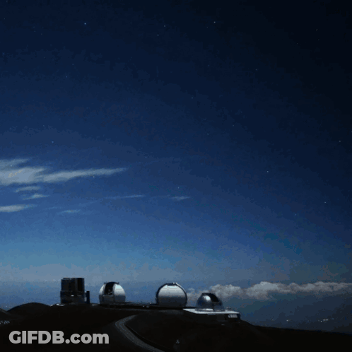 A Bright Light Shines Brightly In The Night Sky Above A Building GIF