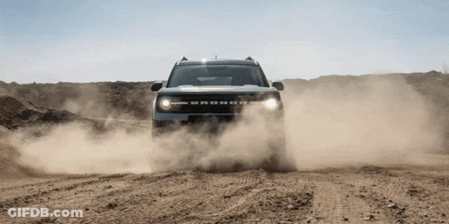 A Bronco Is Driving Through A Dirt Field GIF