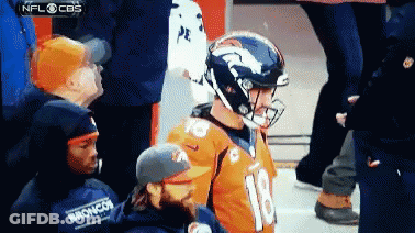 A Broncos Football Player Wearing A Helmet Stands In Front Of A Crowd GIF