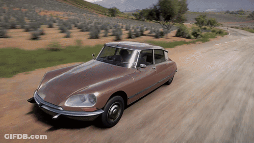 A Brown Car Is Driving Down A Dirt Road With Trees In The Background GIF