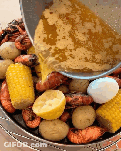 A Bucket Filled With Shrimp Corn Potatoes And Lemons Is Being Poured With Sauce GIF