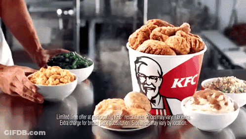 A Bucket Of Fried Chicken Sits On A Counter Next To Bowls Of Macaroni And Cheese And Mashed Potatoes GIF