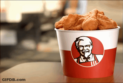 A Bucket Of Kfc Fried Chicken Sits On A Wooden Table GIF