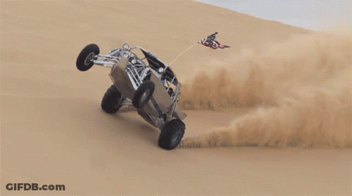 A Buggy Is Going Down A Sand Dune With A Flag On Top GIF