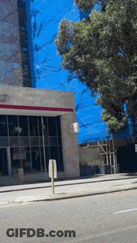 A Building With A Sign That Says No Parking On The Side Of It GIF