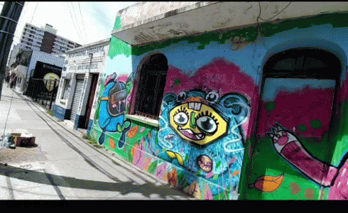 A Building With Graffiti On The Side Of It Including A Cartoon Face GIF