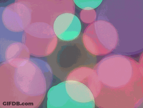 A Bunch Of Bubbles Are Floating In A Dark Room GIF