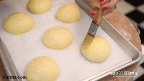 A Bunch Of Buns Are Sitting On A Tray With A Bigger Bolder Baking Logo On The Bottom GIF