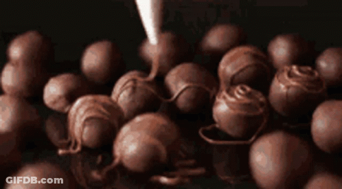 A Bunch Of Chocolate Balls Are Being Covered With Chocolate GIF