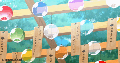 A Bunch Of Colorful Balls Hanging From A Wooden Beam With Chinese Writing On Them GIF