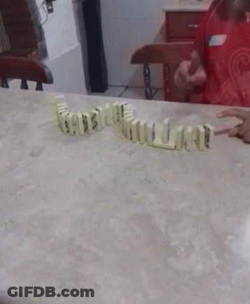 A Bunch Of Dominoes On A Table With A Person In A Red Dress In The Background GIF