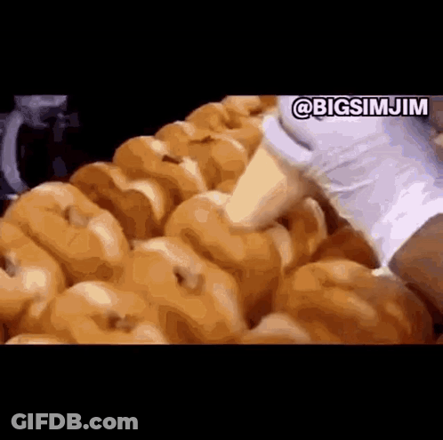 A Bunch Of Donuts Are Being Made In A Donut Shop . GIF