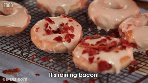 A Bunch Of Donuts Are Sitting On A Cooling Rack With The Words It 'S Raining Bacon GIF