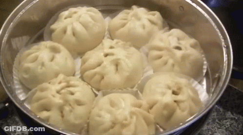 A Bunch Of Dumplings Are Cooking In A Steamer . GIF