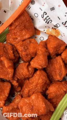 A Bunch Of Fried Chicken Wings With Celery And Carrots On A Paper That Says Shc GIF