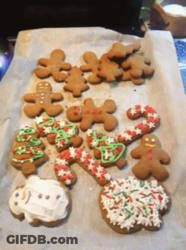 A Bunch Of Gingerbread Cookies Are Sitting On A Tray GIF
