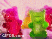 A Bunch Of Gummy Bears In Different Colors Are Sitting On A Table GIF