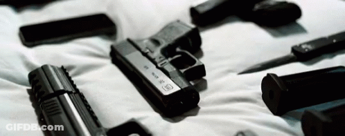 A Bunch Of Guns Are Laying On Top Of A Bed . GIF