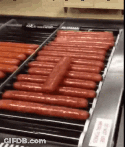 A Bunch Of Hot Dogs On A Conveyor Belt With A Sign That Says " Do Not Touch " GIF