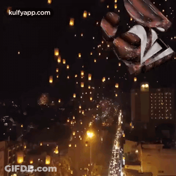A Bunch Of Lanterns Are Flying In The Night Sky Over A City . GIF