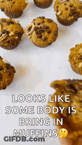 A Bunch Of Muffins Are Sitting On A Table And A Person Is Holding A Piece Of Chocolate Cake . GIF