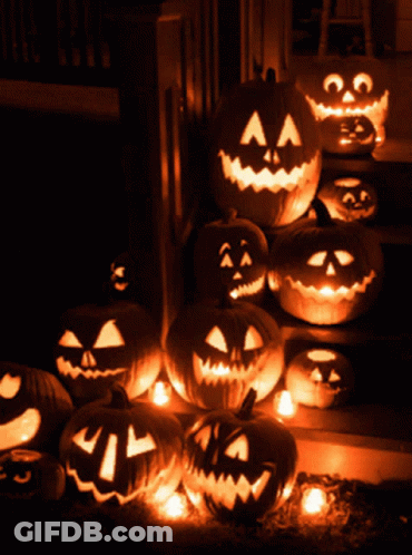 A Bunch Of Pumpkins With Faces Carved Into Them Are Lit Up In The Dark GIF