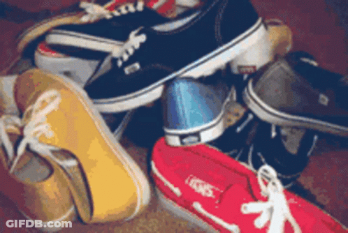 A Bunch Of Shoes Are Stacked On Top Of Each Other And One Of Them Has The Word Vans On It GIF