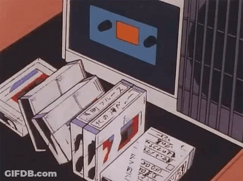 A Bunch Of Tapes Are Sitting On A Table Next To A Cassette Tape Player . GIF