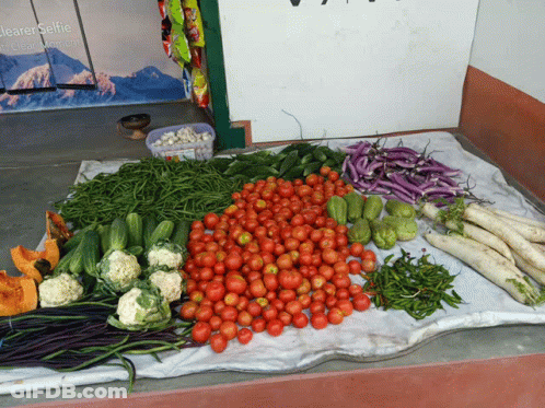 A Bunch Of Vegetables On A Table With A Sign Behind Them That Says Jeaerselfie GIF