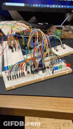 A Bunch Of Wires Are Connected To A Breadboard With A Computer Monitor Behind It GIF