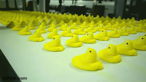A Bunch Of Yellow Rubber Ducks Are Lined Up On A Conveyor Belt GIF