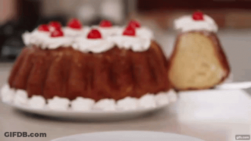 A Bundt Cake With Whipped Cream And Cherries On Top Of It GIF