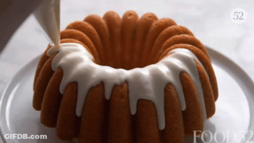 A Bundt Cake With White Frosting Is On A Plate With Food52 Written On It GIF