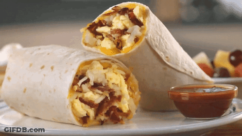 A Burrito Is Cut In Half On A Plate Next To A Bowl Of Sauce GIF