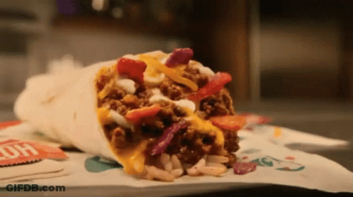 A Burrito With A Lot Of Toppings Is On A Table GIF