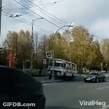 A Bus Is Driving Down A Street Next To A Sign That Says A GIF