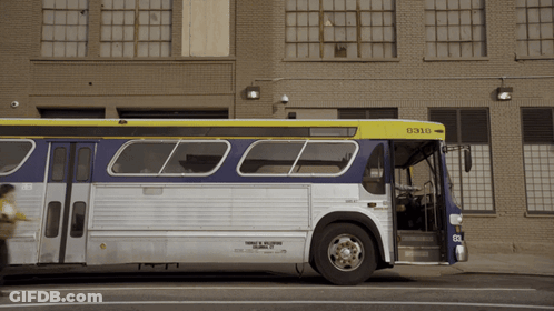 A Bus With The Number 0310 On The Front Is Parked In Front Of A Brick Building GIF