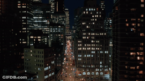 A Busy City Street At Night With A Lot Of Buildings GIF