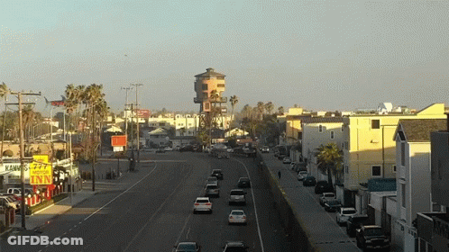 A Busy City Street With A Yellow Sign That Says Motel Inn GIF