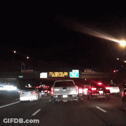 A Busy Highway At Night With A Sign That Says ' Closed ' On It GIF