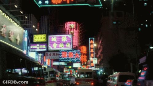 A Busy Street At Night With A Neon Sign That Says ' A ' On It GIF