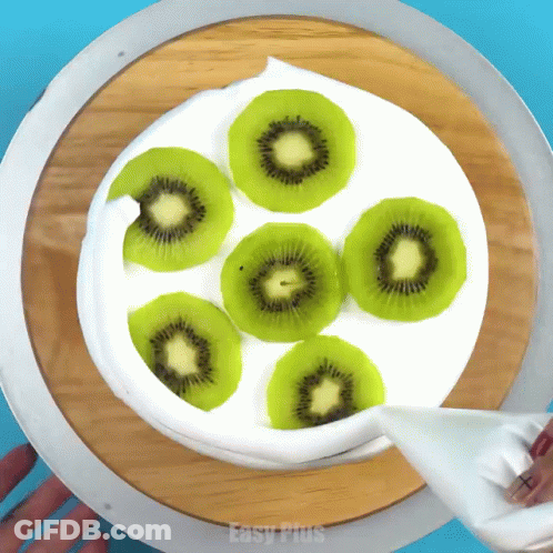A Cake With Kiwi Slices And Whipped Cream Is Being Decorated By Easy Plus GIF